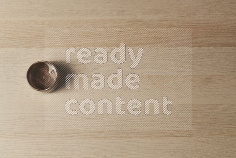 A brown pottery bowl on light wooden background