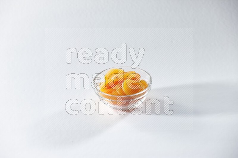 A glass bowl full of dried apricots on a white background in different angles