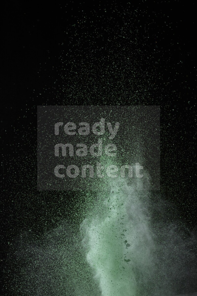 A side view of green powder explosion on black background