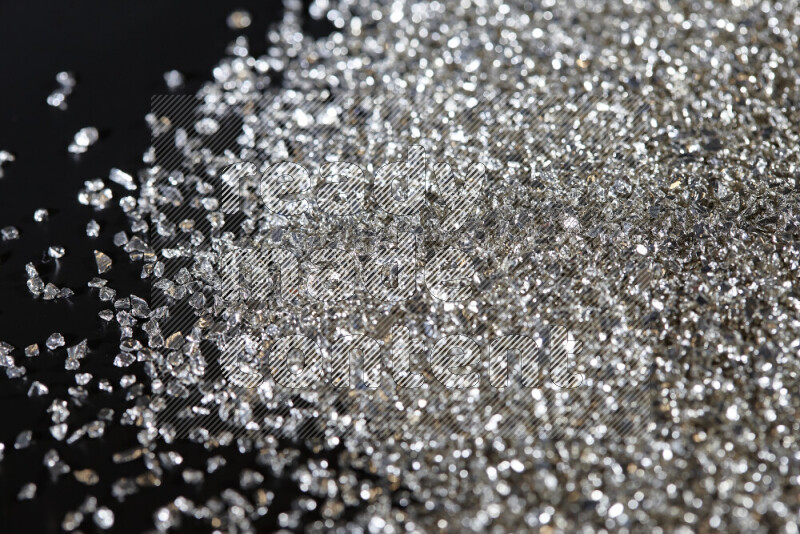 Silver shimmering fragments of glass scattered on a black background