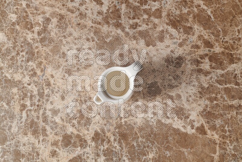 A ceramic milk jug on beige marble background