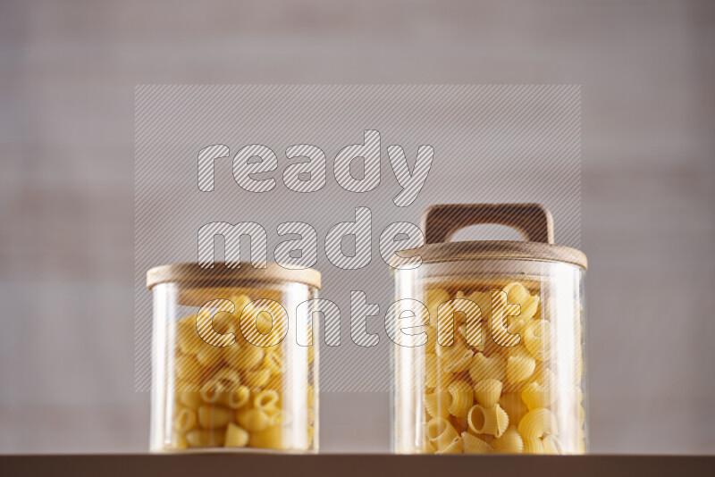 Raw pasta in glass jars on beige background