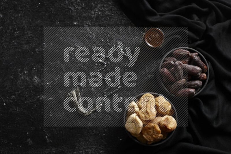 Dried fruits in pottery bowls with coffee in a dark setup