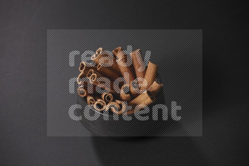 Cinnamon sticks in a black bowl on a black background in different angles