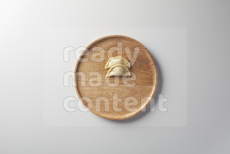Two Sambosas on a wooden round plate on a white background