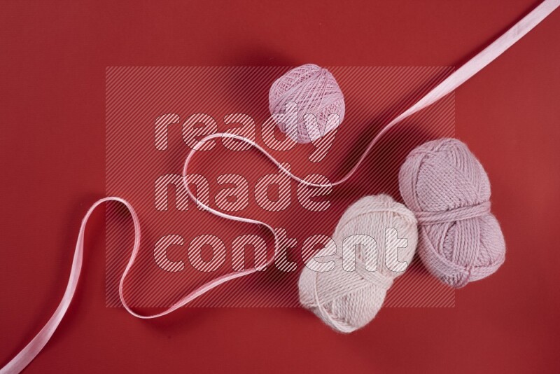 A pink and red collection of sewing and tailoring tools arranged on a red background