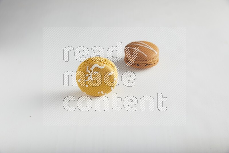 45º Shot of of two assorted Brown Irish Cream, and Yellow Piña Colada macarons on white background