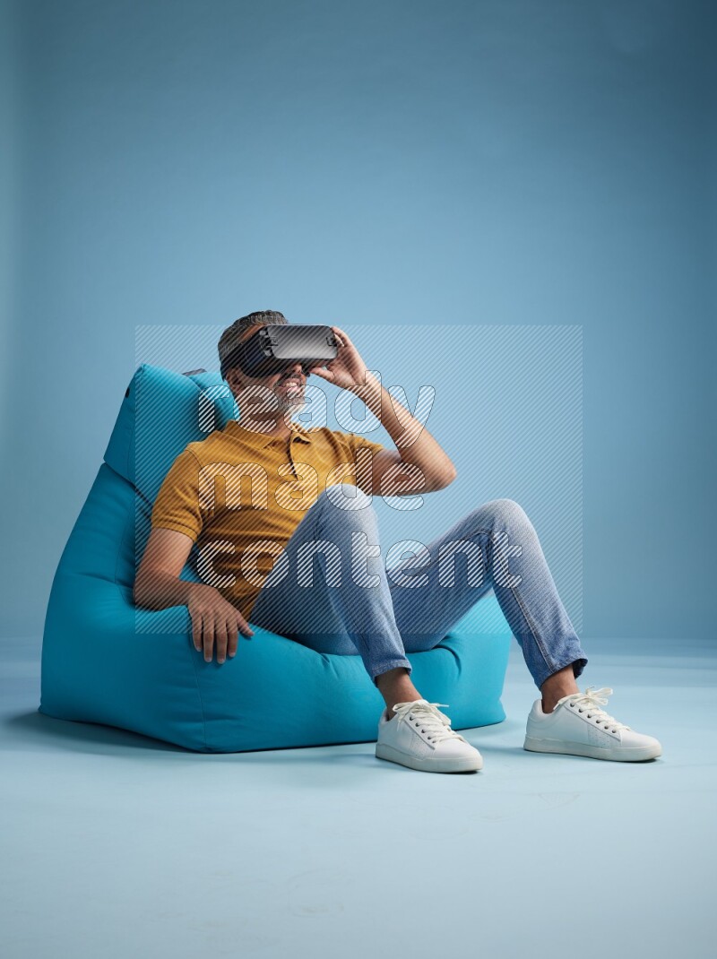 A man sitting on a blue beanbag and gaming with VR