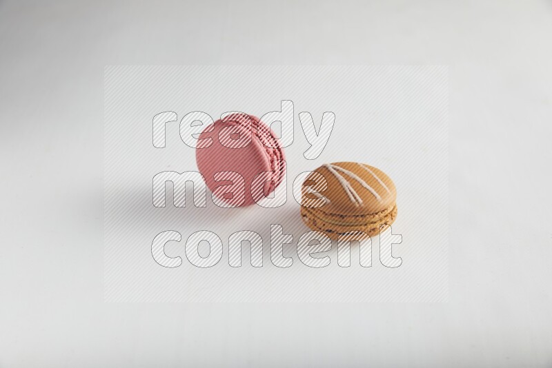 45º Shot of of two assorted Brown Irish Cream, and Pink Raspberry macarons on white background