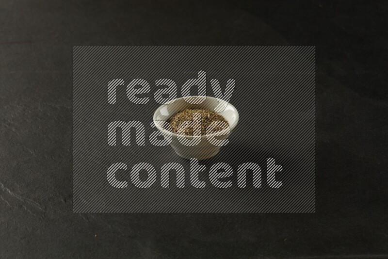wooden round sauce bowl filled with herbs on grey textured countertop