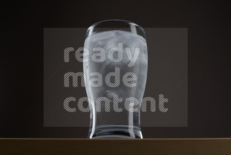 Low angle shot of a glass of water and ice on grey background