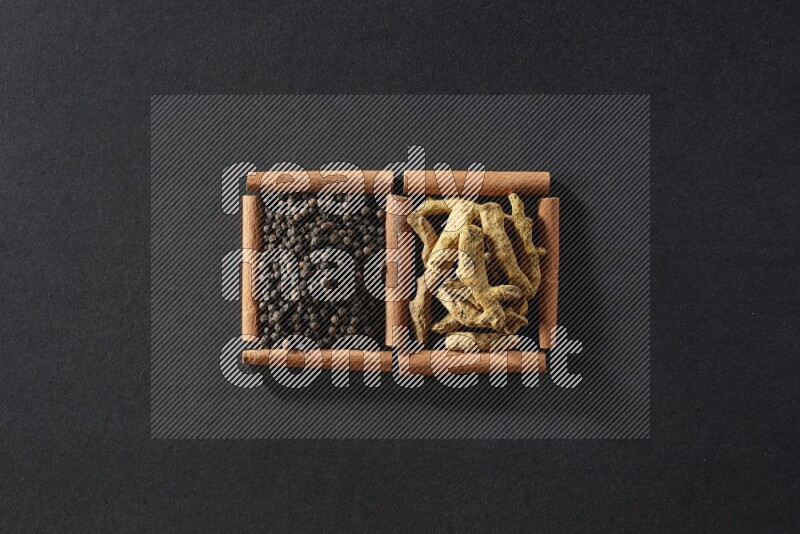 2 squares of cinnamon sticks full of black peppers and turmeric fingers on black flooring