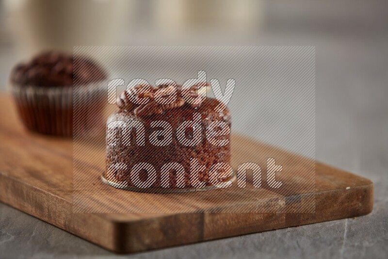 Chocolate cupcake topped with pecan on a wooden board