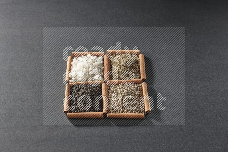 4 squares of cinnamon sticks full of black pepper, cumin, white pepper and white salt on black flooring