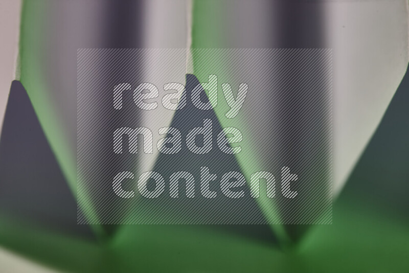 صورة مجردة مقربة تظهر طيات ورقية هندسية حادة بتدرجات اللون الأبيض و الأخضر