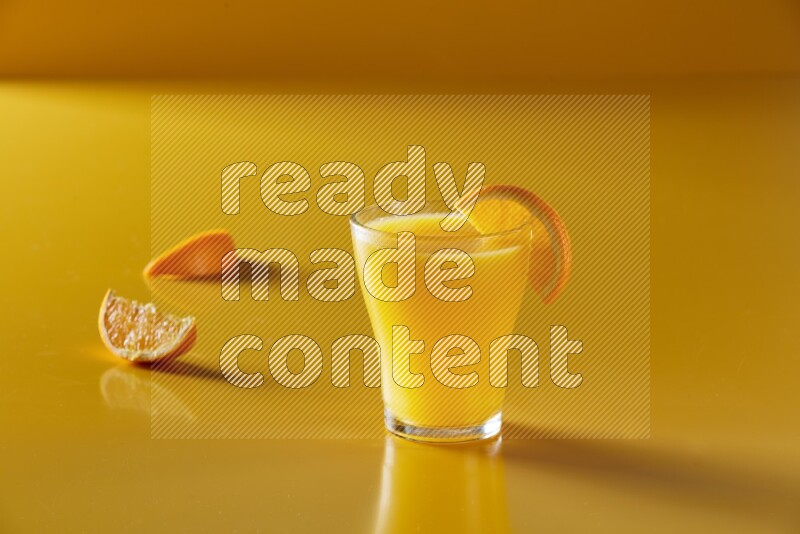 glass of orange juice with orange slice on yellow background