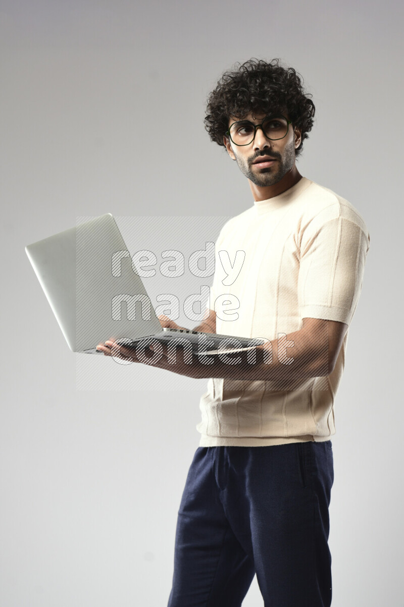 A man wearing casual standing and working on a laptop on white background