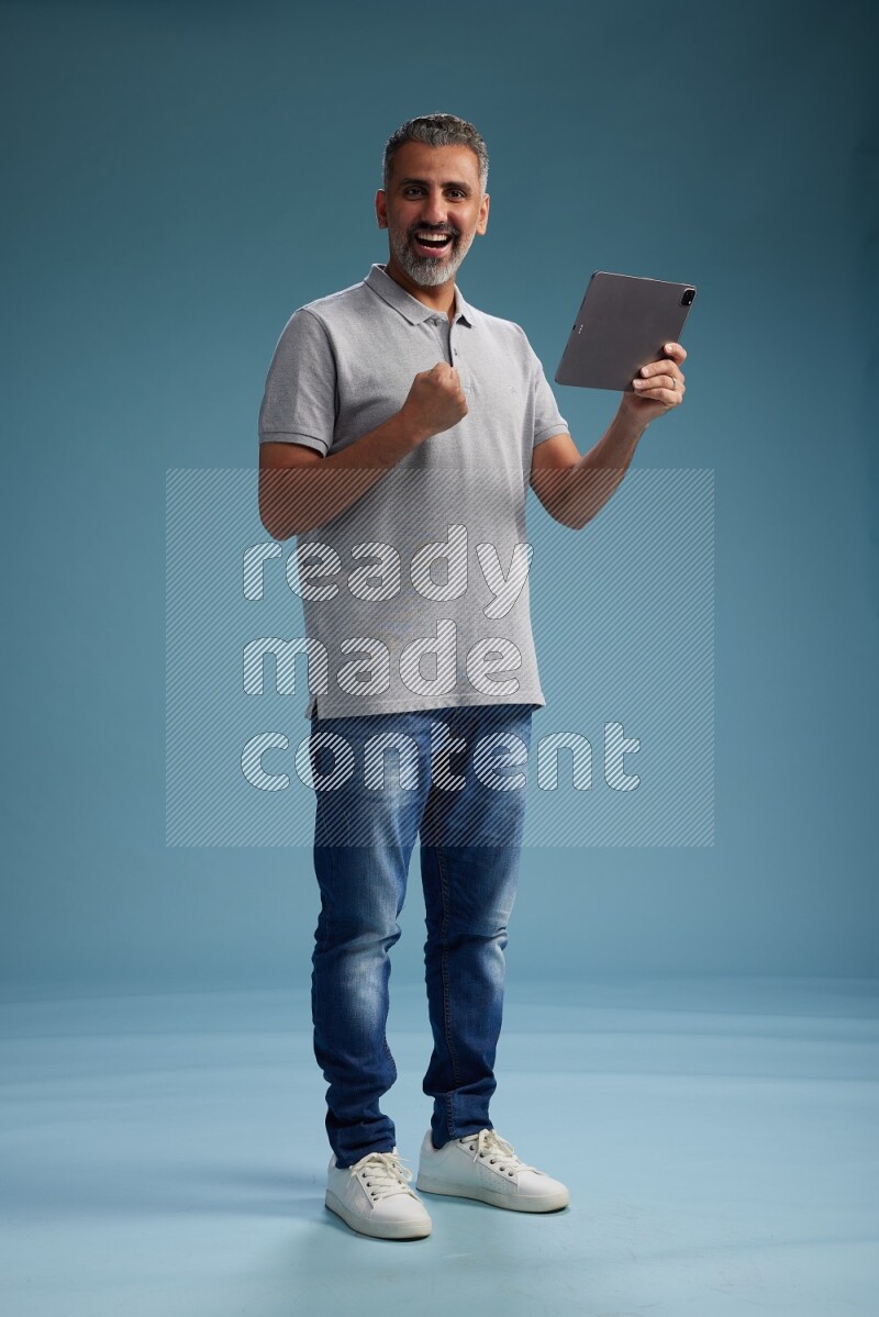 Man Standing working on tablet on blue background