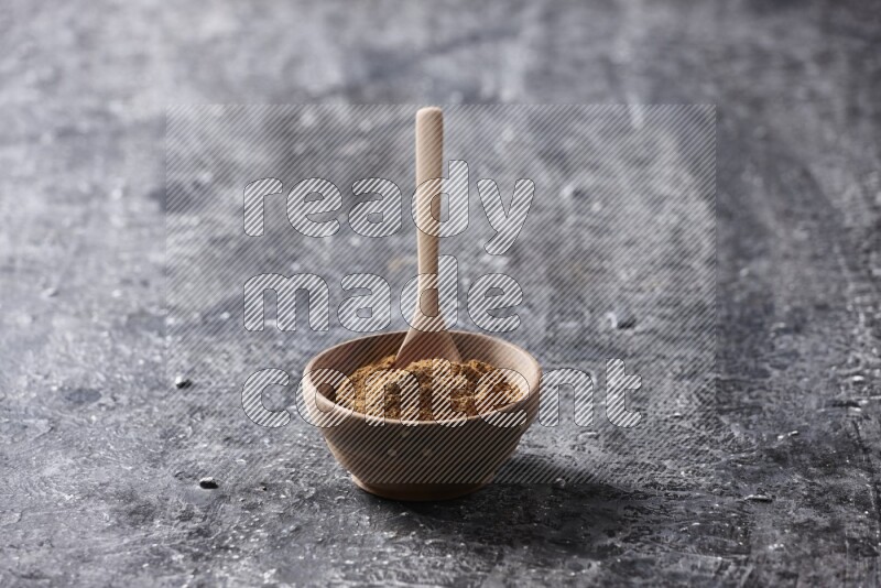 Wooden bowl full of cinnamon powder with a wooden spoon on a textured black background in different angles
