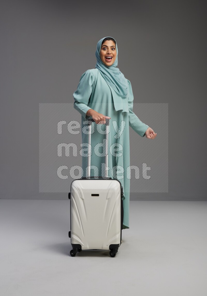 Saudi Woman wearing Abaya standing holding Travel bag on Gray background