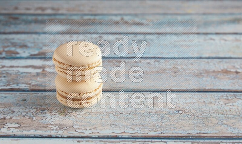 45º Shot of two White Caramel fleur de sel macarons on a light blue wooden background