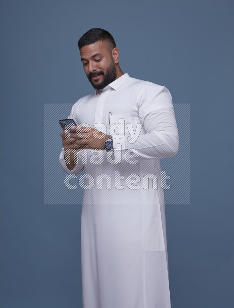 A man Texting on Blue Background wearing Saudi Thob