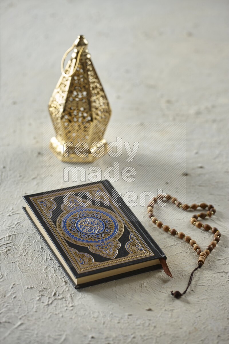 A golden lantern with different drinks, dates, nuts, prayer beads and quran on textured white background