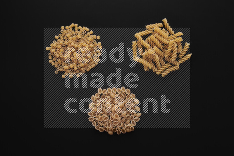 Different pasta types in bunches on black background