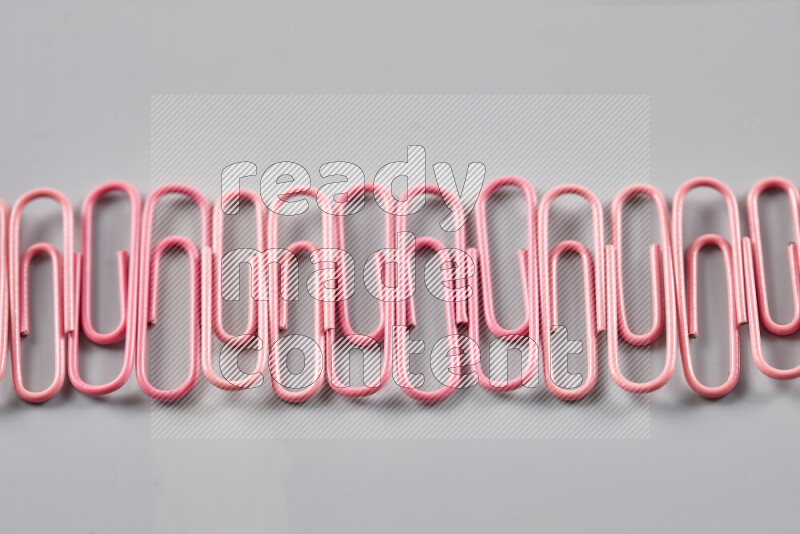 Pink paper clips isolated on a grey background