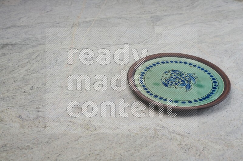 A decorative pottery plate on grey marble background