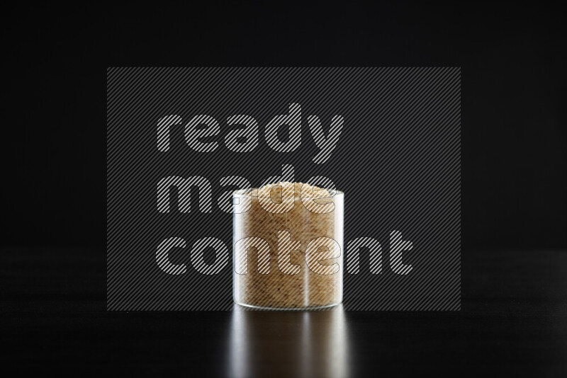 Basmati golden rice in a glass jar on black background