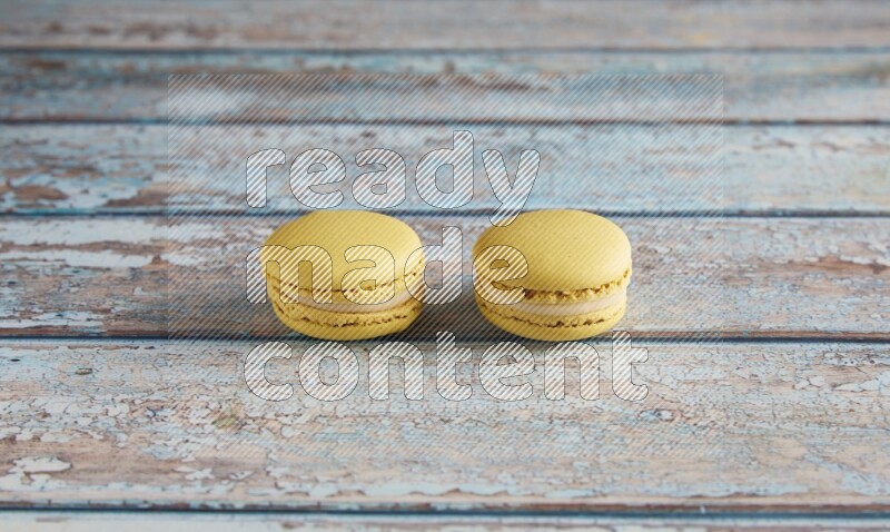 45º Shot of two Yellow Lime macarons on light blue wooden background