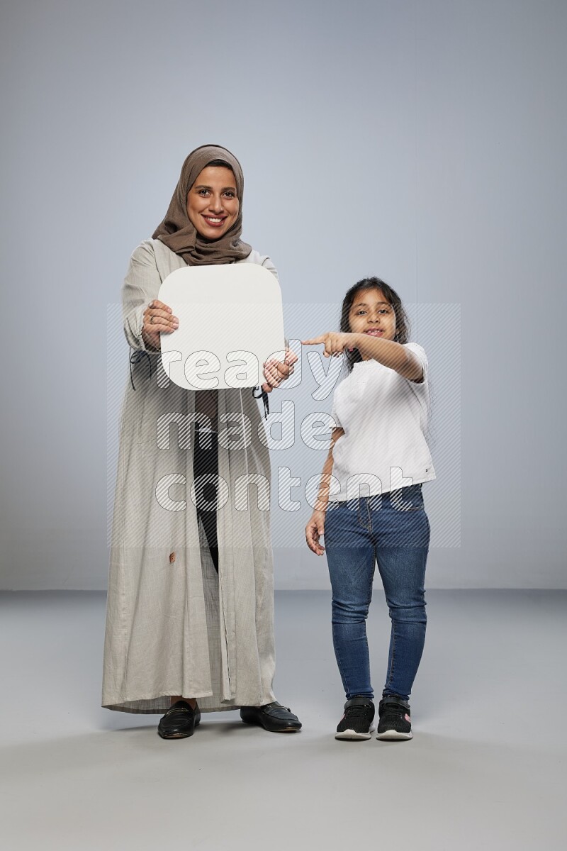 Mom and daughter standing holding social media sign on gray background