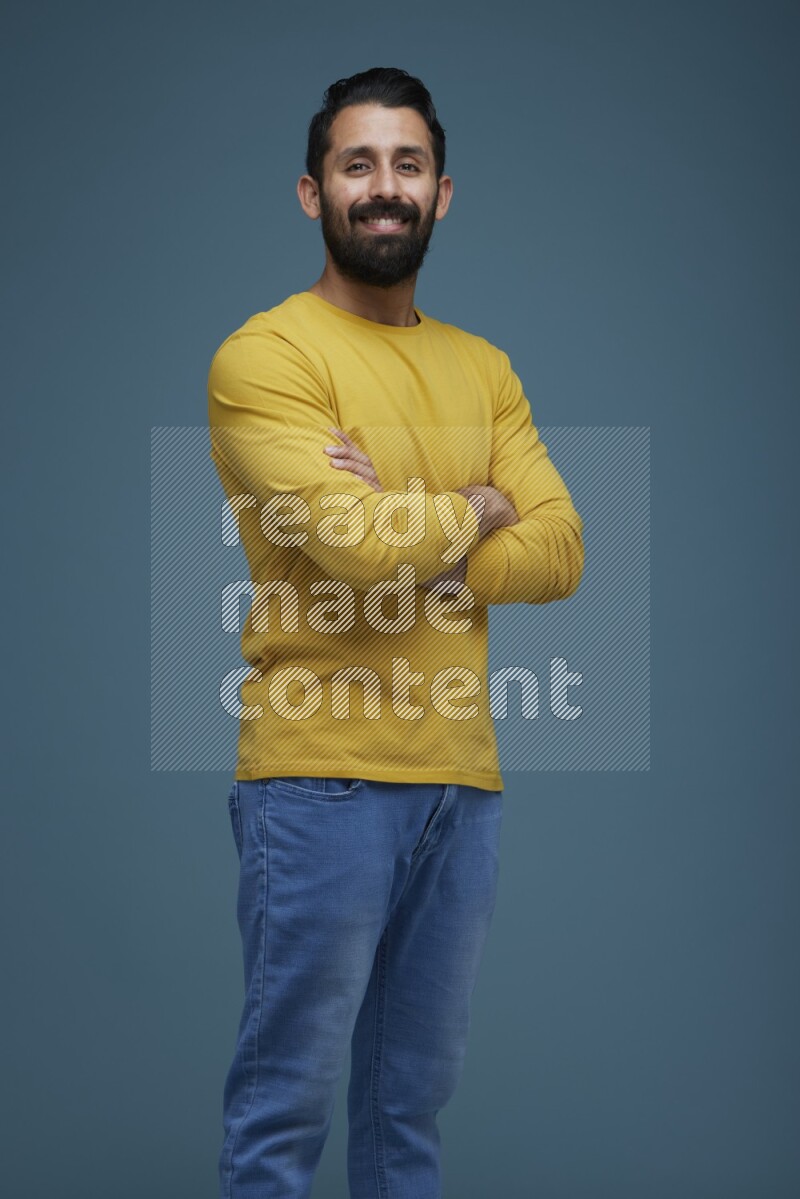 Man posing in a blue background wearing a yellow shirt