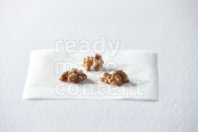 3 peeled walnuts on a piece of paper on a white background in different angles