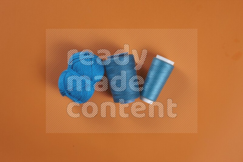 A blue collection of sewing and tailoring tools arranged on a orange background