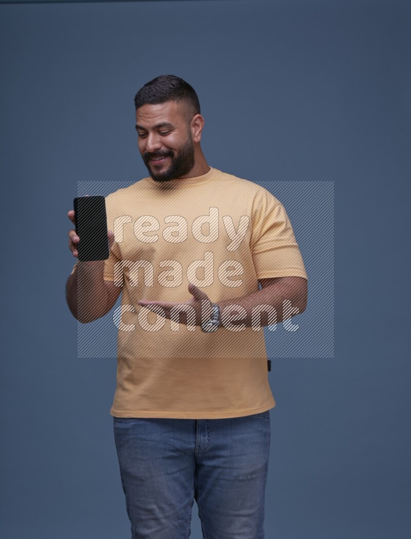 A man Showing His Smart Phone on Blue Background wearing Orange T-shirt