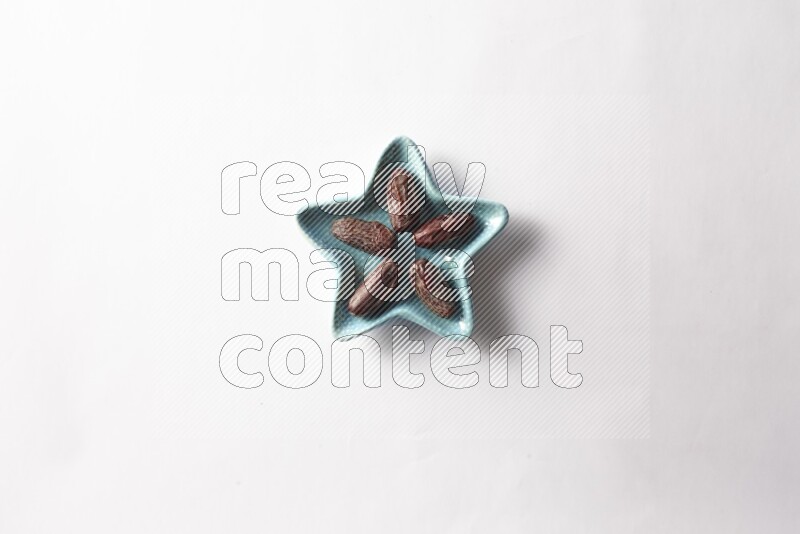 Dates in a star shaped pottery plate on white background