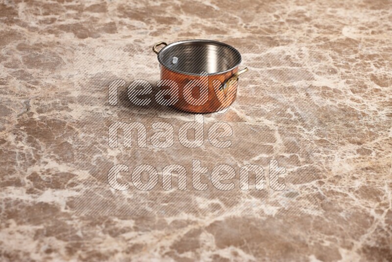 A small copper pot on beige marble background