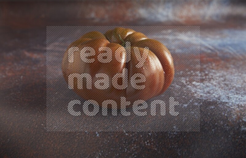 45 degree single heirloom tomato on  a textured reddish rustic metal background