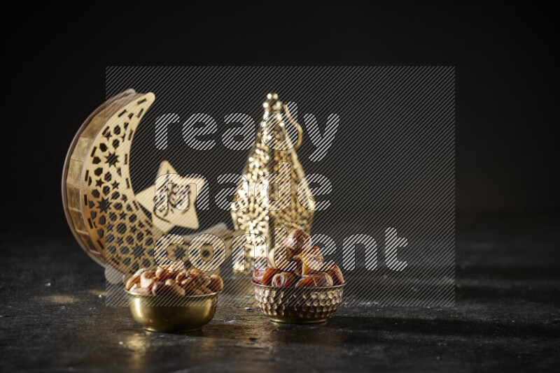 Dates in a metal bowl with mixed nuts beside golden lanterns in a dark setup