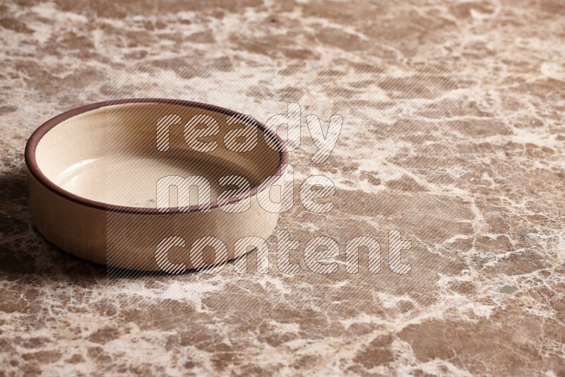 A beige pottery oven plate on beige marble background
