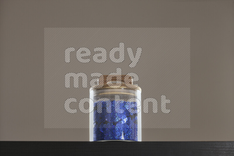 Sequins in a glass jar on black background