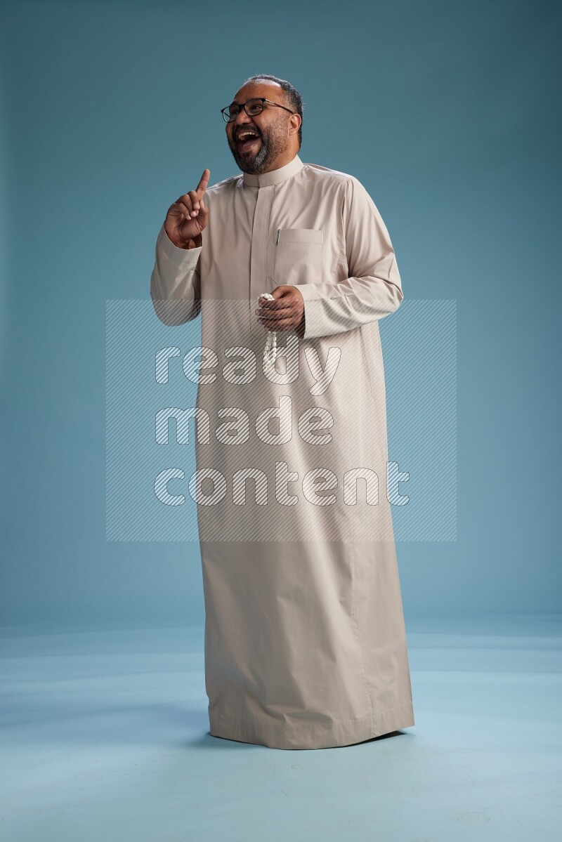Saudi Man without shimag Standing Interacting with the camera on blue background