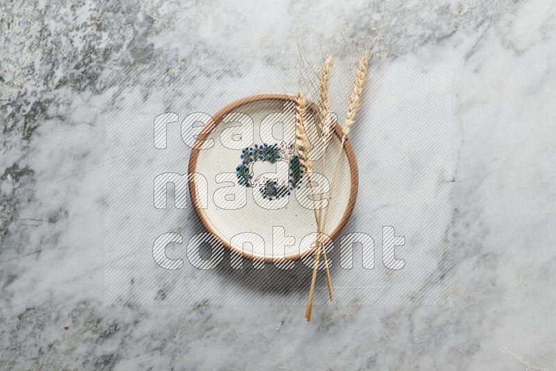 Wheat stalks on decorative pottery plate on grey marble background
