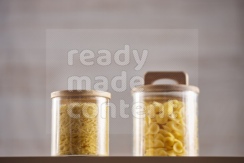 Raw pasta in glass jars on beige background