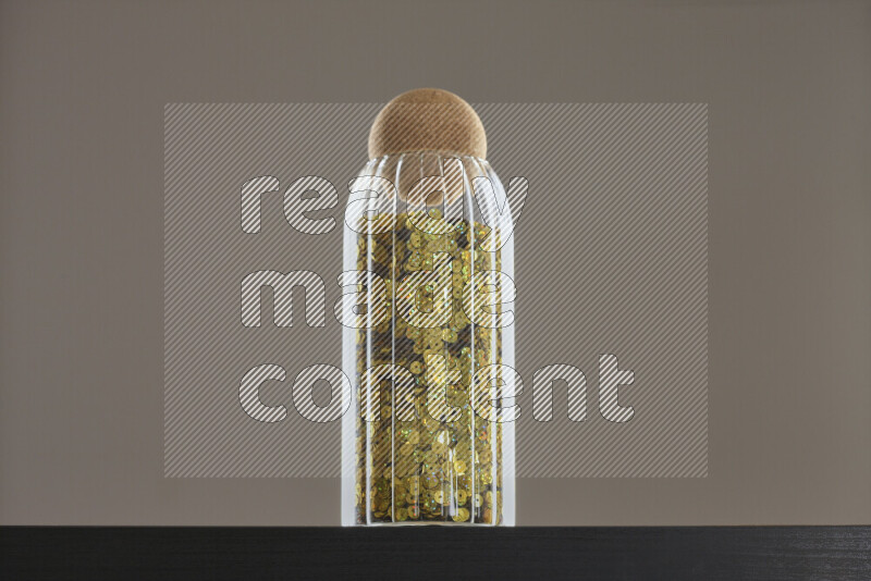 Sequins in a glass jar on black background