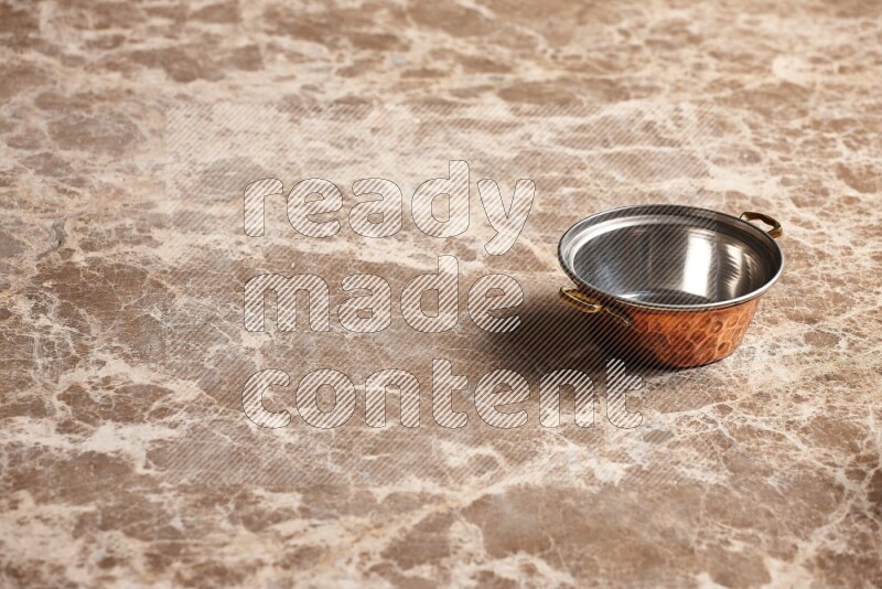 A small copper pot on beige marble background