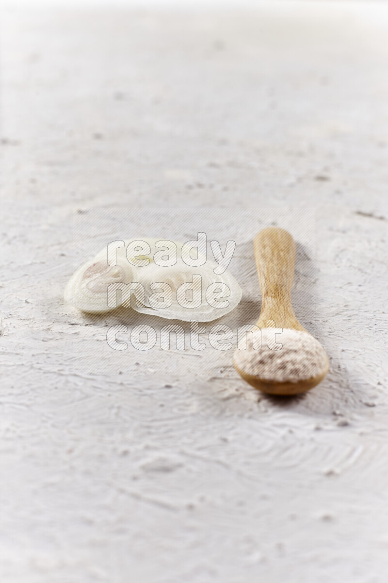 A wooden spoon full of onion powder on white background