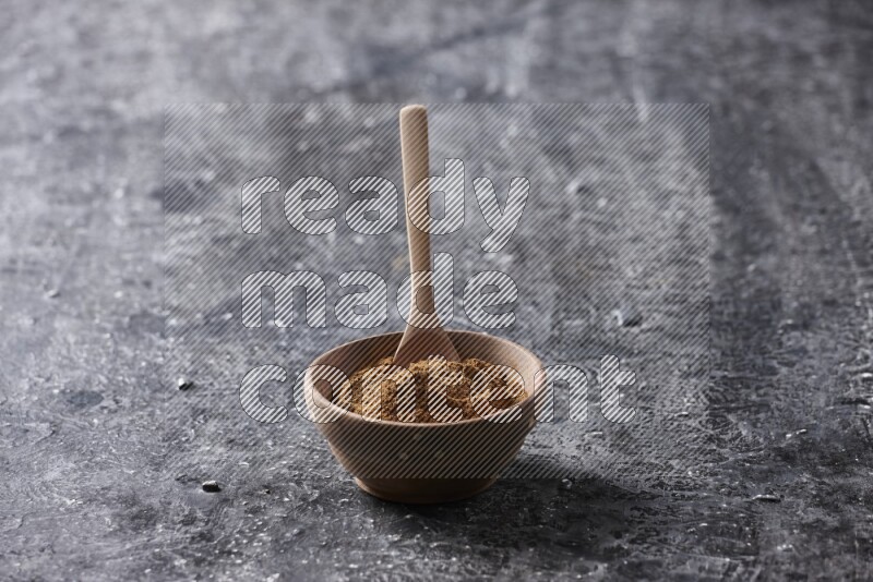 Wooden bowl full of cinnamon powder with a wooden spoon on a textured black background in different angles